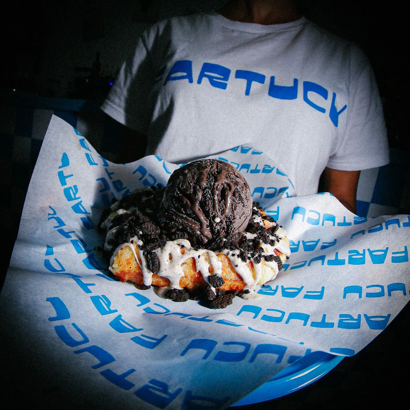 Gofre con helado y Oreo sobre papel antigrasa con la marca Fartucu